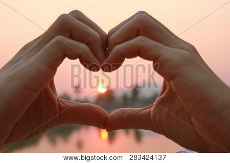 Take  Photo Hands Together To Form A Heart And Light From The Sun In Morning. This Photo Contain Noi