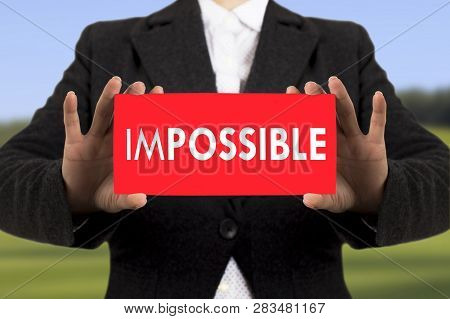 Businesswoman In A Black Jacket Shows A Card With The Inscription Impossible. Selective Focus.