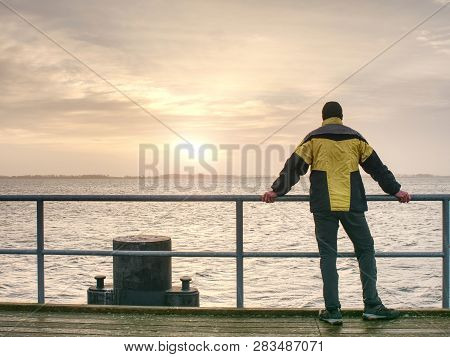 Man Tourist In Autumn Mist On Wooden Pier Above Sea. Depression Dark Atmosphere.