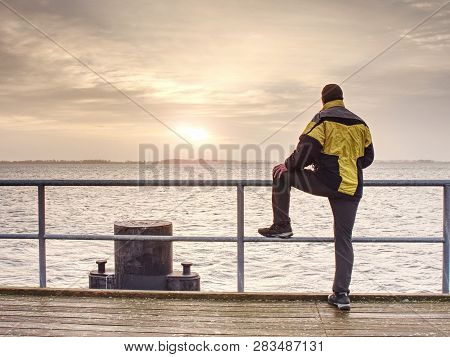 Man Thinking. Tourist In Warm Clothes On Sea Mole At Handrail. Autumn Misty Day. Tourist On Pier In 