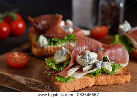 Bruschetta With Prosciutto, Salad Frieze And Cheese On The Kitchen Table. Snack.
