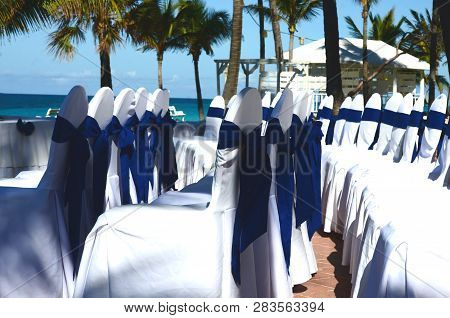 White wedding gazebo in a seaside tropical garden at a destination wedding reception. Decorated chai