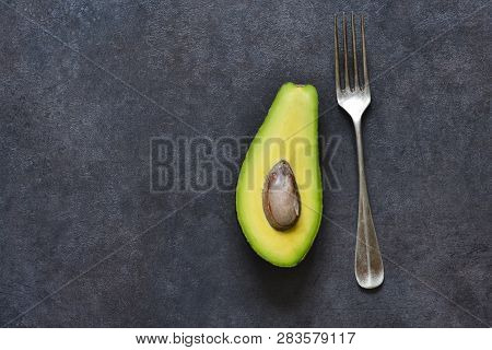 Avocado And Fork On A Black Background With Space For Text. Diet Food.. View From Above.