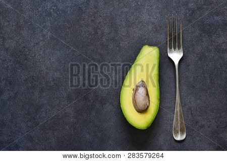 Avocado And Fork On A Black Background With Space For Text. Diet Food.. View From Above.