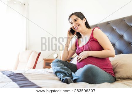 Cheerful Woman Chitchatting On Call While Touching Pregnant Tummy