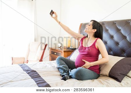 Content Mother To Be Taking Selfportrait On Mobile Phone At Home