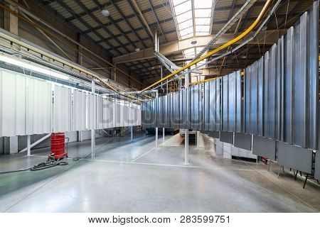 Powder Coating Line. Metal Panels Are Suspended On An Overhead Conveyor Line. Painting Products In A