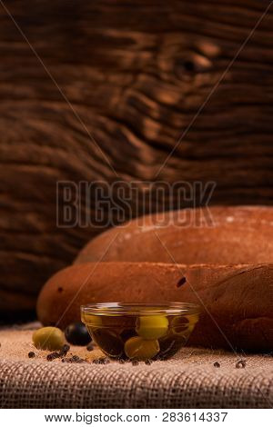 Fresh Bread Baguette With Olive Oil, Olives. Cheese And Rosemary On Wooden Background. Teasty Breakf