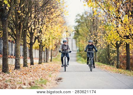 A Senior Couple With Electrobikes Cycling Outdoors On A Road.