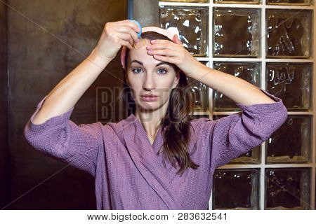 Young Girl In A Purple Robe Stands In The Bathroom And Makes A Pear Face Massage