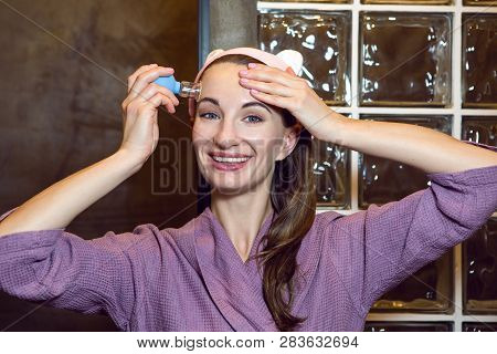 Young Girl In A Purple Robe Stands In The Bathroom And Makes A Pear Face Massage