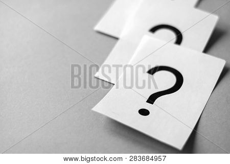 White Cards With Printed Question Marks On Grey Background With Copy Space. Queue Of Questions To Be