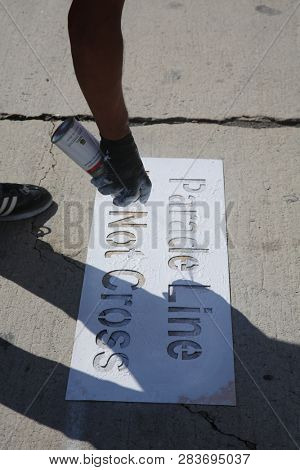 LOS ANGELES - FEBRUARY 9, 2019: Golden Dragon Parade in the streets of China Town Los Angeles. A worker Stencils a Do Not Cross sign on the streets of LA for the Chinese New Year celebration.


