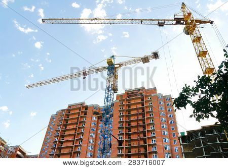 Two Tower Cranes Against The Background Of Buildings Under Construction. Construction Site.