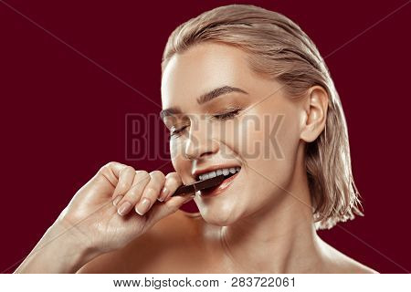 Close Up Of Woman With Natural Makeup Biting Chocolate