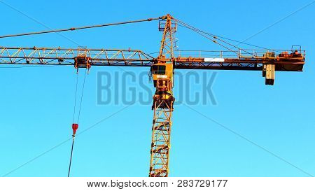 Building Crane Against Blue Sky. Hoisting Crane. Construction Site. Industrial Crane.