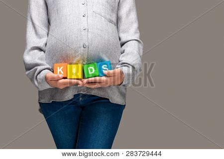Partial View Of Pregnant Asian Woman In Grey Shirt And Blue Jeans Holding Alphabet Cubes With Word K