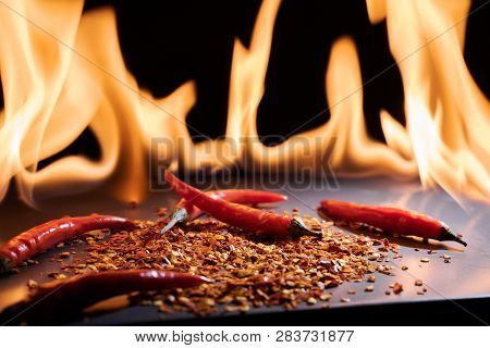 Red Chili Peppers. Sharp Red Siliculose Pepper Against A Flame.