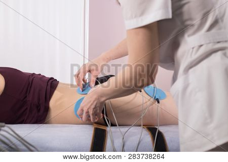 Cosmetology Beauty Clinic. Young Woman Taking Myostimulation, Lying In Bed, Side View
