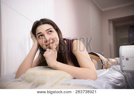 Cosmetology Beauty Clinic. Young Woman With Dark Hair Taking Myostimulation, Smiling And Looking Up 