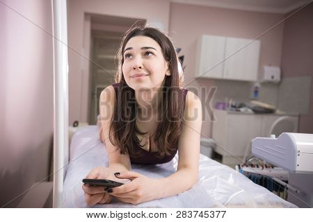 Portrait Of Woman Taking Myostimulation And Holding Her Phone At The Nutritionists Office