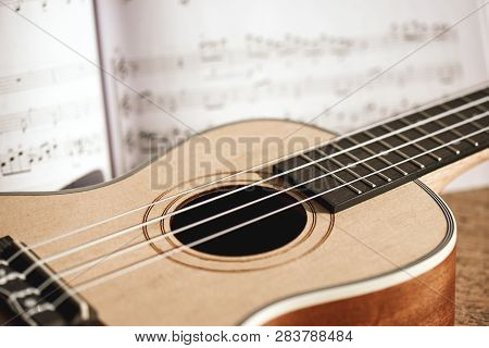 Ukulele Chords. Close-up Photo Of Ukulele Guitar And Music Notes Against Of Wooden Background. Music