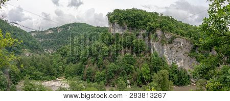 Skybridge Suspension Bridge Over A Gorge Over A Precipice And A River On A Cloudy Day. Green Forest 