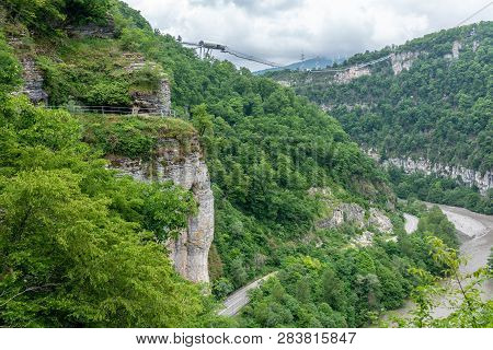 Skybridge Suspension Bridge Over A Gorge Over An Abyss With A River And Serpentine Road On A Cloudy 