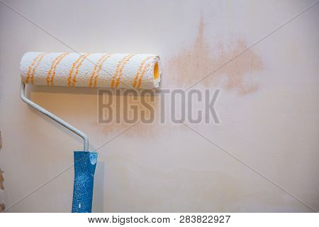 Close Up Of Painter Arm Painting A Wall With Paint Roller