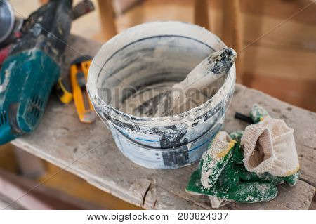 Working Gloves. Do Makeovers. Putty Knife Lying On The Bucket. Tools For Construction And Repair. Se