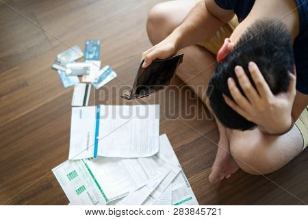 Top View Of Stressed Young Asian Man Holding Empty Wallet And Thinking About  Finding Money To Pay C