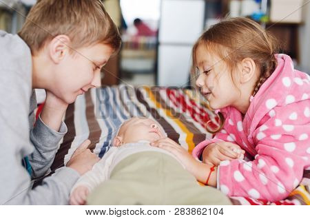 Big Brother And Sister Playing With Baby Brother At Home
