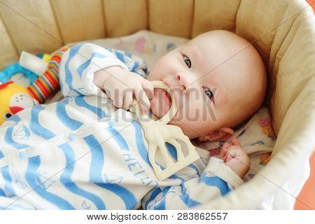 Baby With Teether Toy In The Crib