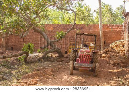 Redi, Maharashtra/ India - 02.01.2019: Red Indian Tractor With Hindcarriage Near Green Tree On The B