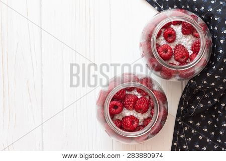 Glass Jars Of Pudding From Chia Seeds With Coconut Milk And Raspberry Berries In White Wooden Table.