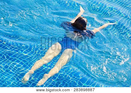 Top View Of Woman Swimming In A Pool. Straight Body, Slim Woman. Swim And Fitness Concept.