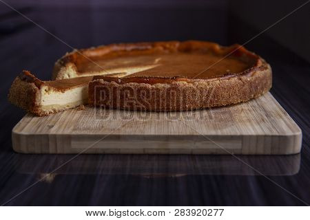 One Slice Of Pie Cut From Round Fresh Backed Cheesecake On Wooden Board.