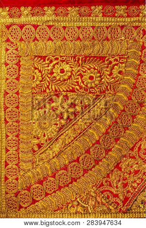 Close up of beautiful and intricately hand-woven Indian golden fabric or saree.