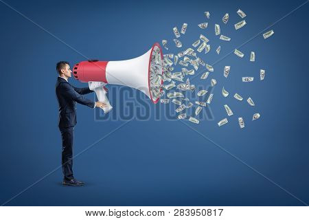 A Side View Of A Businessman Holding A Disproportionately Big Loudspeaker With Lots Of Dollar Bills 