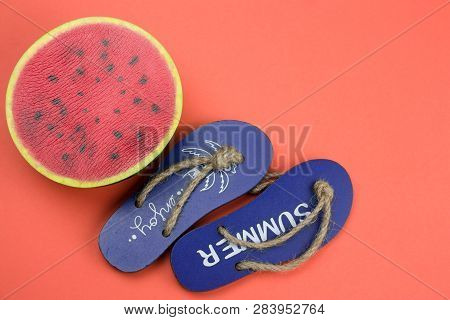 Top View Decorative Wooden Flip Flops And Squishy Toy Watermelon  On A Coral Background Copy Space