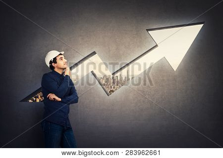 Wise Engineer, Wearing Protective Helmet, Holding Hand Under Chin Thoughtful Looking Up In Front Of 