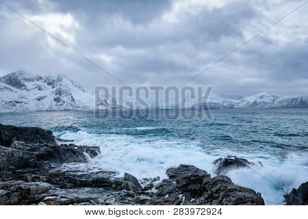 Waves of Norwegian sea crushing at rocky coast in fjord. Vikten, Lofoten islands, Norway