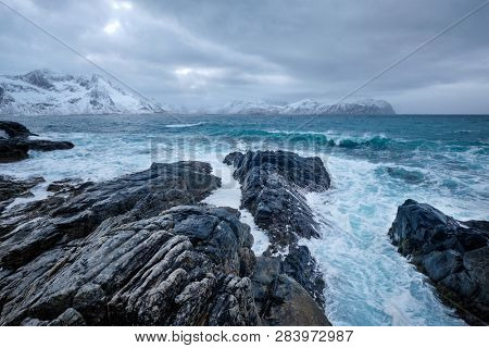 Waves of Norwegian sea crushing at rocky coast in fjord. Vikten, Lofoten islands, Norway
