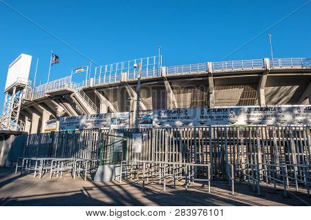 The Exterior Of The Football Stadium Where Atalanta Plays. Atalanta Flag. On Background A Blue Sky. 