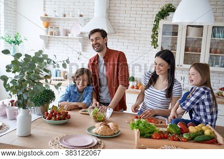 Happiness. Young Beautiful Family Preparing A Salad Together In The Modern Kitchen At Home. Mother A