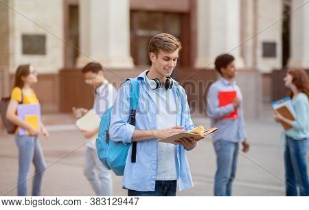 University Student Guy Reading Book Learning Standing Outside College Building. Getting Degree, High