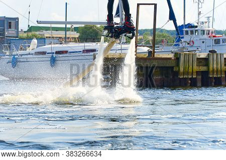 Man Having Fun On Flyboard. Flyboarding In A Sunny Summer Day At River In Harbor. Extrime Water Acti