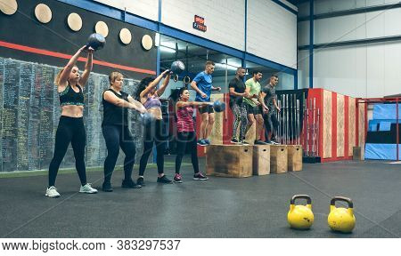 Sportswomen Exercising With Kettlebells And Sportsmen Doing Box Jumps