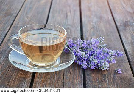 Cup Of Healthy Hot Lavender Tea And Bouquet Of Flowers A Wooden Table. Concept Of A Healthy Lifestyl