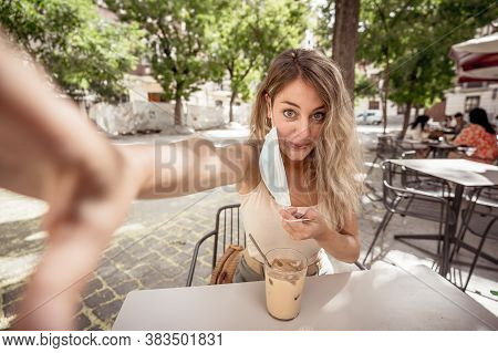 Woman Wearing Protective Face Mask On Mobile Video Calling Friends In Coffee Shop In The New Normal